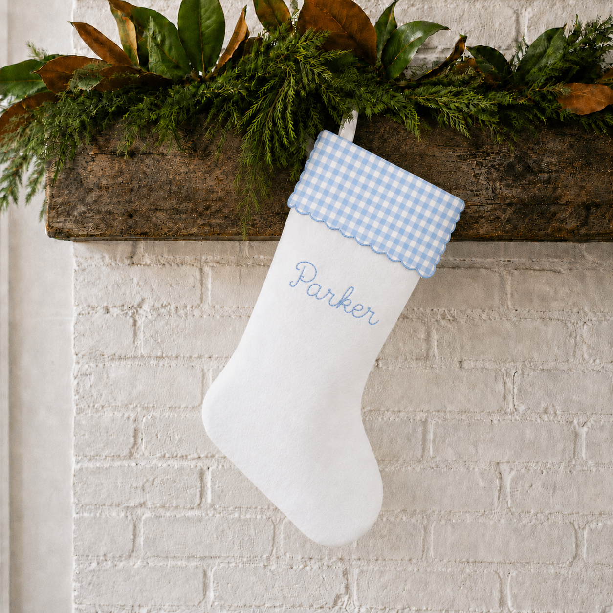 Personalized Christmas stocking with blue gingham scalloped cuff styled on a holiday mantel
