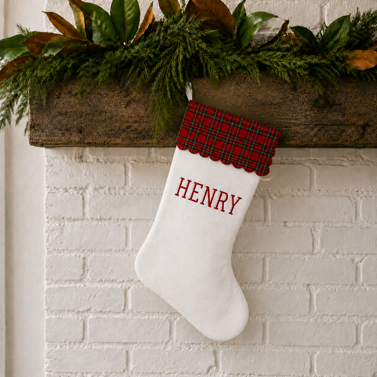 Personalized Christmas stocking with red tartan scalloped cuff styled on a holiday mantel